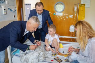 Jakub Vaněk klukovi na posteli ukazuje jak sestavit Lego